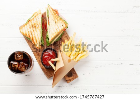 Club sandwich, potato fries chips and glass of cola drink with ice. Fast food take away. Top view with copy space