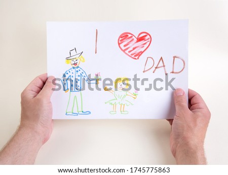 hands hold a drawing of a child. Father's Day Congratulations Concept. High quality photo