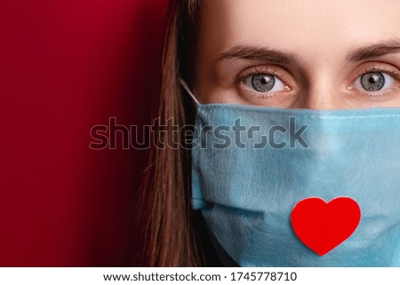 Cropped portrait of woman isolated on red background wearing a medical mask with heart on it as a way to show thank, nurses and medical staff working in hospitals during coronavirus COVID-19 pandemics