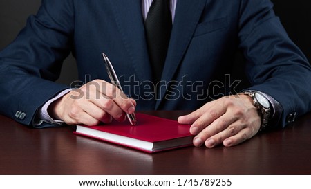 business disappointment concept. businessman in formal wear sitting at the desk and holds silver pen at his arm.