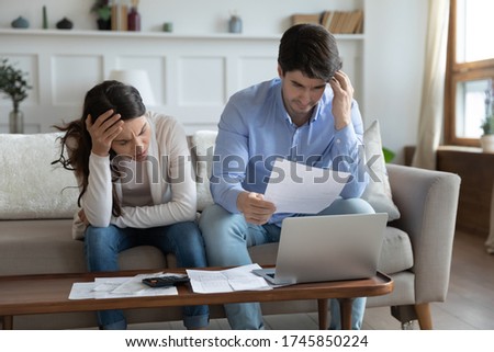 Anxious young caucasian couple feel stressed managing household finances documents paperwork together, worried man and woman distressed about bankruptcy, have financial problem pay bill online Royalty-Free Stock Photo #1745850224