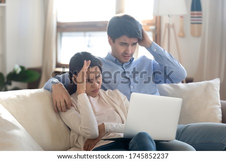 Frustrated young man and woman sit on sofa at home concerned by unpleasant unexpected news online, unhappy caucasian couple distressed with eviction email or notification, or having laptop problems Royalty-Free Stock Photo #1745852237
