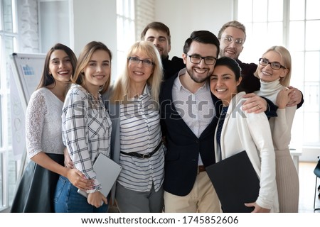 Portrait of emotional positive bonding diverse business people, posing for photo in office. Overjoyed excited friendly young and middle aged mixed race teammates embracing, looking at camera. Royalty-Free Stock Photo #1745852606