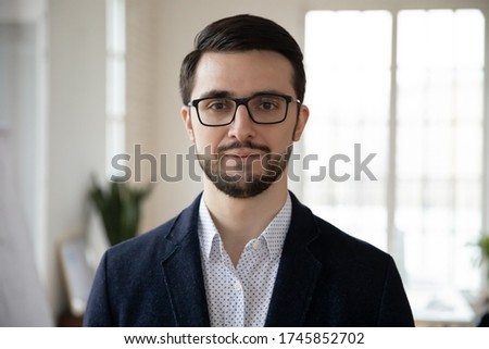 Head shot close up portrait of young confident businessman in eyeglasses. Smart professional bearded coach trainer speaker ceo executive in formal wear posing for photo alone, looking at camera. Royalty-Free Stock Photo #1745852702