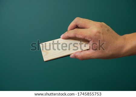 Hand holding brush eraser on green Background. Clipping path. teacher and school supplies.