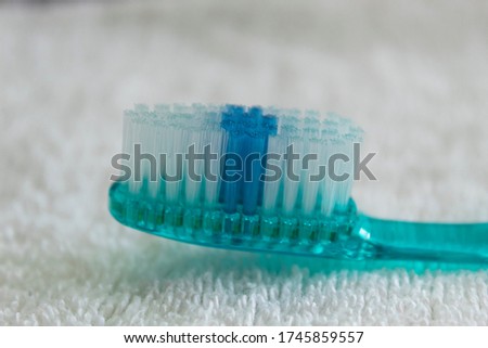 Macro photography to a blue thooth brush with white tufts and blue head over a blurred white towel background.
