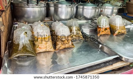 Picture of Thai food stall with plastic bags containing various curry that looks appetizing.
