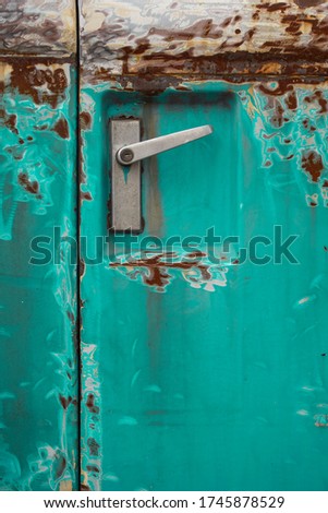 Poor quality paint on the car, cracks and scratches on the rusty metal surface. Abstract pattern, texture, pattern detail background with rusty stains. A car door handle on an old green car