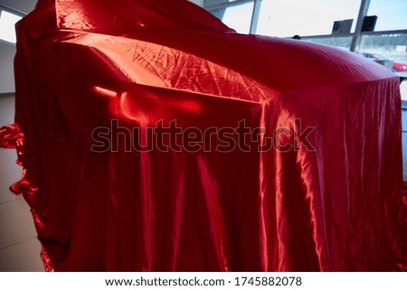Car is covered with red cloth as a gift