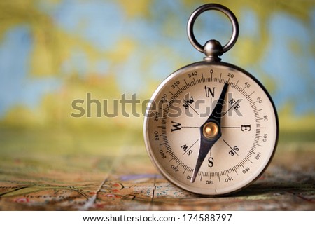Magnetic compass standing upright on a world map conceptual of global travel , tourism and exploration, with copyspace Royalty-Free Stock Photo #174588797