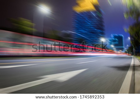 At night, wide motion blurred roads on the side of urban high-rise buildings