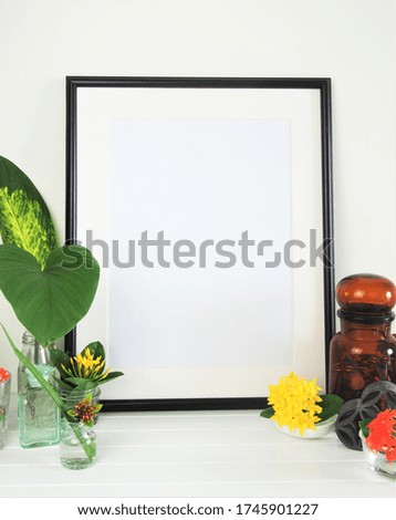 The picture frame with flowers arrange in the glasses