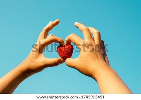 Woman hand holding a red heart and make to heart shape. symbol of mercy and peace concept.