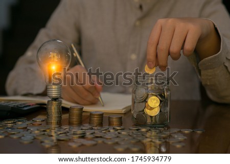 Business finance and saving power saving money by hand puting coins in jug glass 
