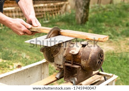 Construction contractor worker using a worm-driven hand-held circular saw to cut boards.