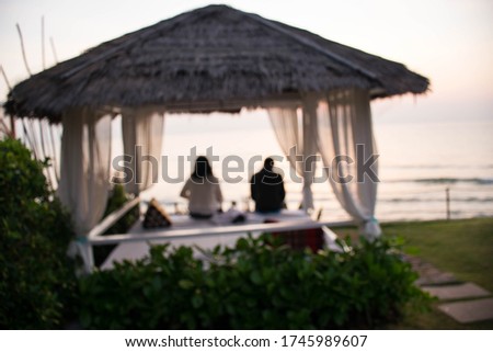 Blurred Rear view of  woman and boy sitting on cozy white lounger on the beach.