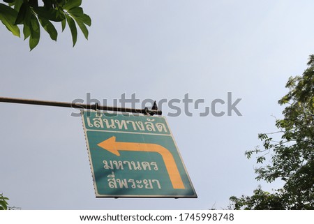Signs for shortcuts on roads in Thailand with trees covering  But can be seen.
