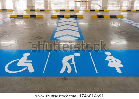 Parking space reserved for elderly people, disabled person, and pregnant women only, painted in blue and white on asphalt road with traffic dividing lines.