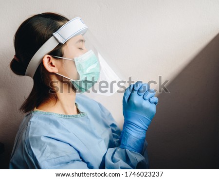 Healthcare worker praying for god blessing while wearing safety equipment for working in hospital during coivd-19 pandemic. Conceptual of woman praying for god to help everythings will be better. Royalty-Free Stock Photo #1746023237