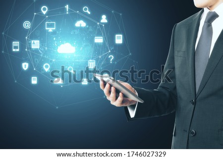 Businessman holding tablet with glowing social network icons. Business and communication concept.