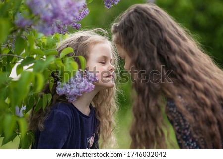 Outside is a portrait of two sisters among the lilac bushes.