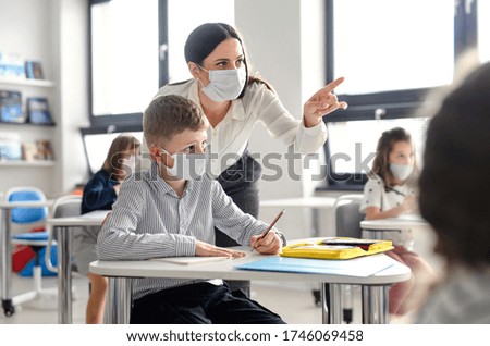 Teacher and children with face mask back at school after covid-19 quarantine and lockdown. Royalty-Free Stock Photo #1746069458
