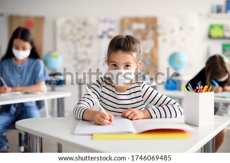 Child with face mask back at school after covid-19 quarantine and lockdown, writing. Royalty-Free Stock Photo #1746069485