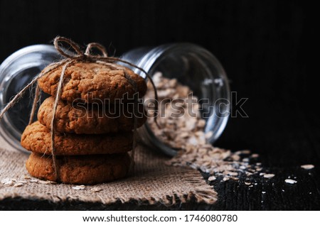 homemade oatmeal cookies tied with a thread on a natural linen napkin. It lies on a dark wooden background. rustic style