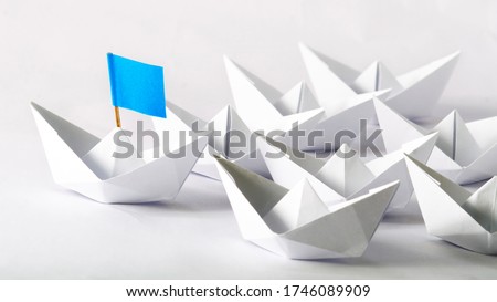 Leadership concept. Blue flag Origami White Paper boat (ship) leading the others.  One leader ship leads other ships.
 Royalty-Free Stock Photo #1746089909