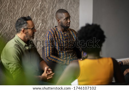 Young African American businessman talking with a group of colleagues during a meeting in an office