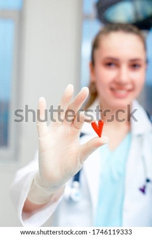 Smiling female doctor holding a heart in her hands. The concept of medetsine, saving lives. Heart as a symbol of life. copies of the space.
