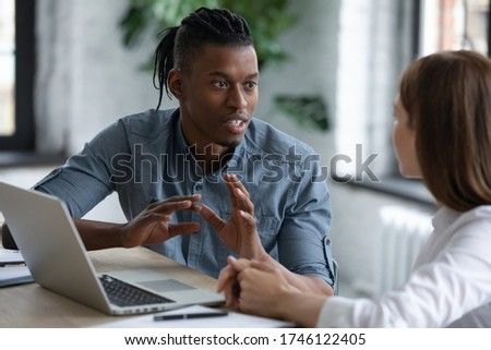 Confident African American team leader mentor teaching new employee, giving instructions to businesswoman, diverse colleagues sharing ideas, working on project together, discussing strategy Royalty-Free Stock Photo #1746122405