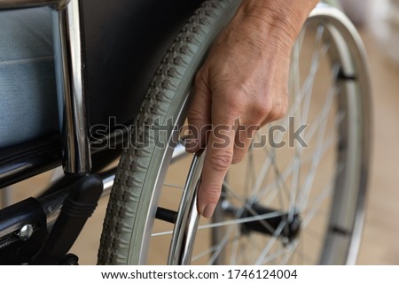 Close up view elderly female hand on rotary ring of self-propelled wheelchair. Concept of handicapped disabled person, movement disorder loss of muscle function caused by age, senile disease, accident Royalty-Free Stock Photo #1746124004