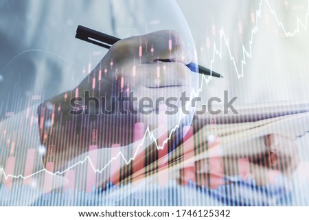 Abstract creative financial graph with world map and with man hand writing in notebook on background, forex and investment concept. Multiexposure
