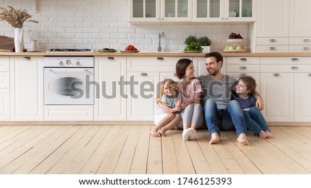 Happy young family with little children sit on warm wooden floor in new modern design kitchen, overjoyed parents with excited small kids relax rest in own renovated apartment, moving concept Royalty-Free Stock Photo #1746125393