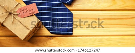 gift box with a canvas ribbon with a greeting tag. next to it is a blue tie. father's day concept. postcard with space for text