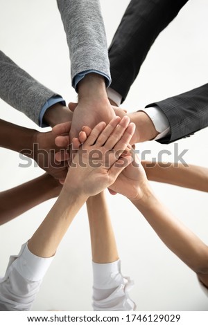 Close up bottom view vertical photo diverse business people stacking hands in pile at corporate meeting, colleagues employees engaged in team building activity at briefing, celebrating shared success Royalty-Free Stock Photo #1746129029