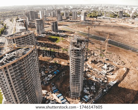 
New district under construction in the city center. Aerial view of a construction site with tall cranes, buildings and infrastructure.