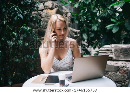 Skilled digital nomad using roaming internet for service consultancy about system update for laptop computer, Caucasian woman searching information on website while receiving smartphone call