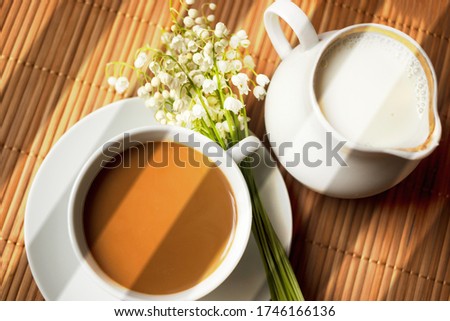 Cup of coffee on a saucer with lilies of the valley