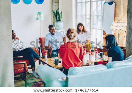 Hipster friends playing in cards sitting at gather table in modern home apartment, happy people spending time together on gambling entertainment enjoying leisure weekend for live socialising Royalty-Free Stock Photo #1746177614