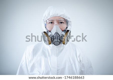 Scientist or Virologist man wearing biohazard chemical protective suit, goggles and mask. Male doctor or medical worker wearing PPE and rubber gloves for preventing Coronavirus (COVID-19) infection. Royalty-Free Stock Photo #1746188663