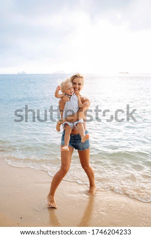 Happy mom on vacation hugs her little laughing son