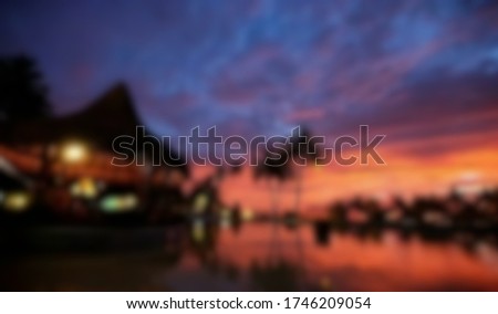 abstract blur background sunset late evening scene red blue sky a hut on the bank of a river with dark palm tree blurred
