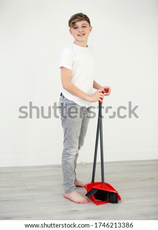a boy with a broom in the room cleans. Housekeeping concept.Looking camera