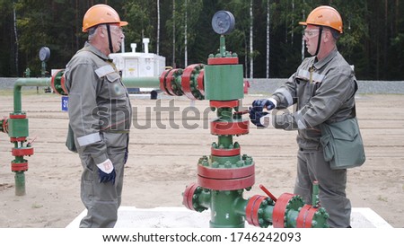 Man oil engineer overseeing Cross type X-mass tree destined for wellhead sealing, their operating regime regulation, installation of electric-centrifugal pump, adjunction of devices for well testing.