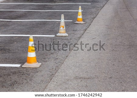 Orange road cones on a asphelt driving area with white lines
