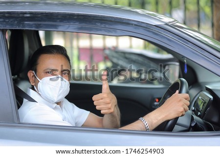 Man in car wearing mask giving thumbs up. Driving car with mask on. Protection against covid-19. Drive safely.  Royalty-Free Stock Photo #1746254903