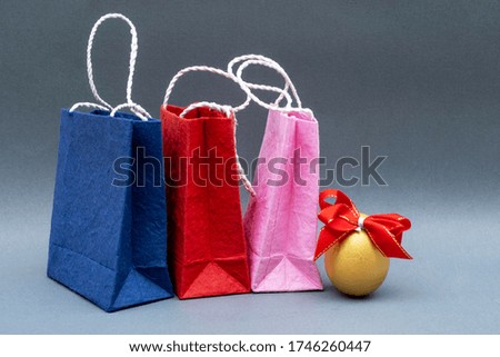 Golden Egg with red Ribbon and shopping bags isolated on gray background.