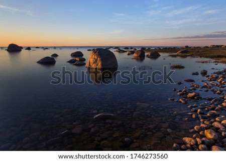 Baltic sea coast with stones and a beautiful sunset, long exposure photograph as a background for a postcard